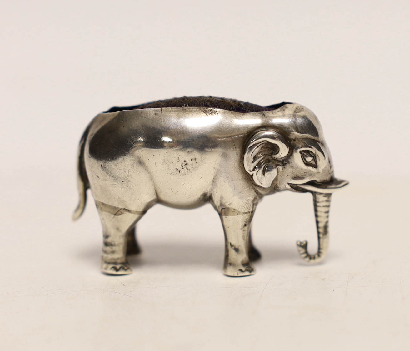 An early 20th century novelty silver pin cushion, modelled as a small elephant, Sydney & Co, Birmingham, date letter rubbed, 42mm.